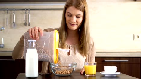 Beautiful-young-attractive-woman-pouring-cerealin-a-bowl-for-breakfast-in-the-kitchen