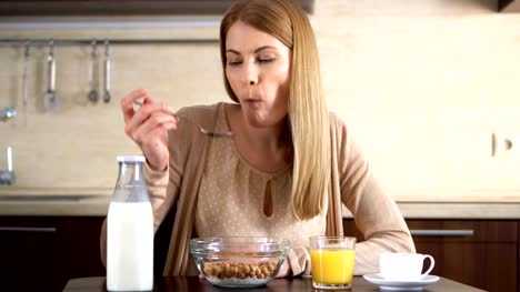 Beautiful-young-attractive-woman-eating-cornflakes-for-breakfast-in-kitchen.-Cup-of-coffee