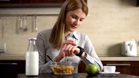 Schöne-Geschäftsfrau-frühstücken-und-mit-ihrem-smart-Uhr.-Internet-surfen.-Lesen-von-Nachrichten