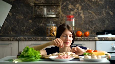 schöne-lächelnde-Frau-Koch-spielen-mit-Gemüse-auf-dem-Tisch-in-der-Küche-zu-Hause