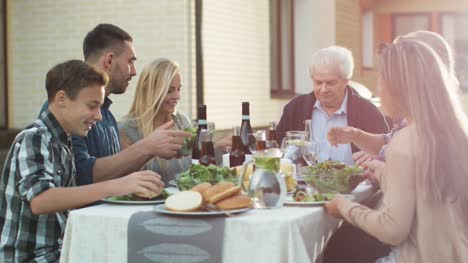 Grupo-de-personas-de-raza-mixta-teniendo-diversión,-comunicación-y-comer-en-la-cena-al-aire-libre-de-la-familia