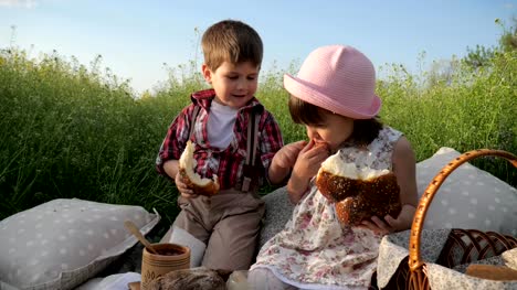 happy-Girl-and-boy-eating-bakery,-Cute-little-kids-sharing-bread,-brother-and-sister-having-fun-playing-in-fresh-air,-healthy-food