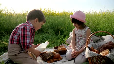 Children-and-nature,-Friends-on-green-lawn,-picnic,-Boy-and-girl-with-food-on-nature,-Happy-children-in-fresh-air,-Boy-pours-milk