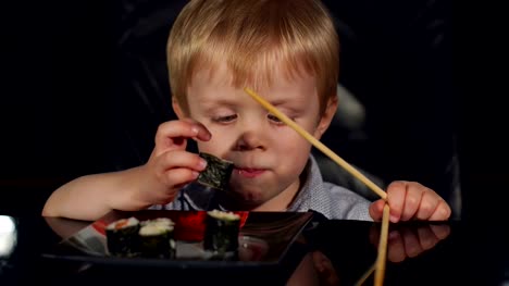 Close-up-of-child-eating-sushi-on-black-background