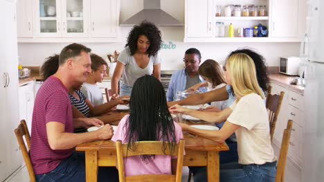 Two-Families-With-Teenage-Children-Eating-Meal-In-Kitchen