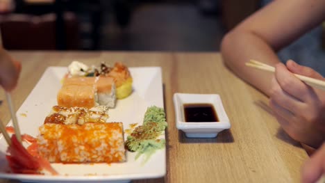 Amigos-comer-rollos-de-sushi-en-el-restaurante-de-Japón