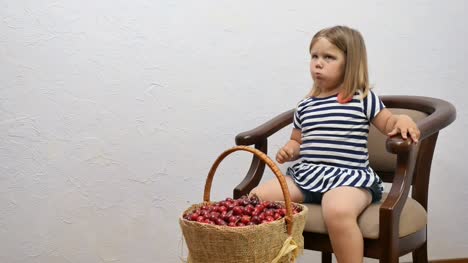 Cute-little-girl-eat-a-cherries-at-the-chair