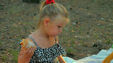 Entzückendes-kleine-Mädchen-essen-Croissant-im-park