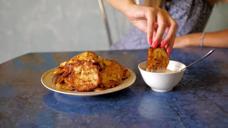 Young-Woman-Takes-Delicious-Fried-Vegetable-Pancake,-Dunked-In-Sauce-And-Eat