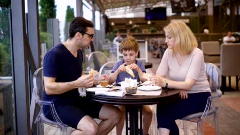 A-happy-family-dines-at-a-restaurant,-a-husband-and-wife-ordered-a-pizza,-their-little-son-is-pleased-with-the-delicious-choice-of-his-parents
