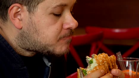 Hungry-man-bytes-a-big-burger.Close-up-on-man-eating-burger