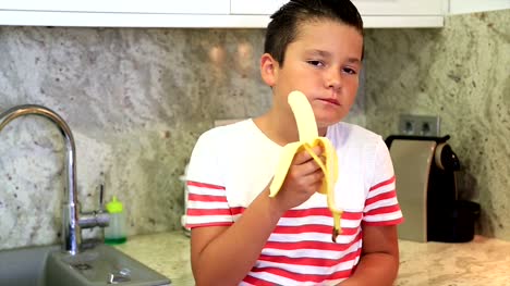 Young-boy-eating-banana-in-the-kitchen