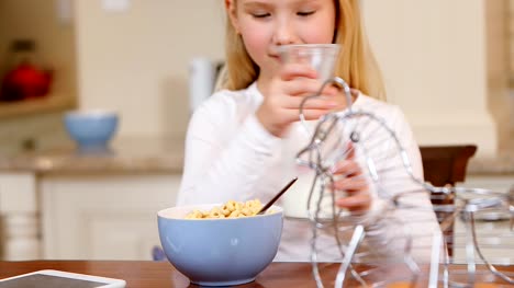 Little-girl-pouring-milk-into-breakfast-in-the-kitchen-4K-4k
