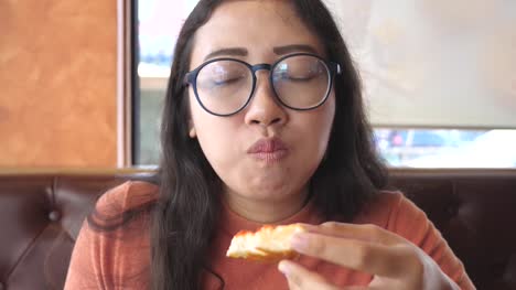 Young-woman-eats-pizza-in-restaurant
