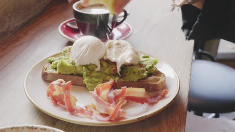 Woman-Squeezing-Lemon-Over-Poached-Egg-And-Avocado-On-Toast