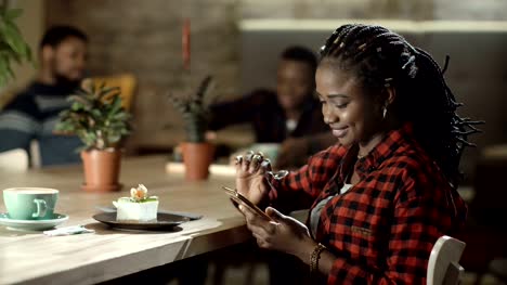 Smiling-black-woman-with-phone-in-cafe