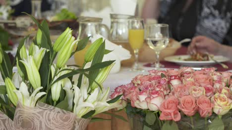 Festlich-gedeckten-Tisch-mit-Blumenarrangements-aus-Lilien-und-Rosen-verziert