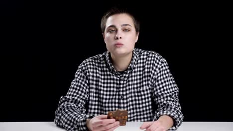 Young-unordinary-girl-is-eating-bar-of-chocolate,-diet-conception,-black-background