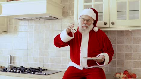 Santa-sits-on-kitchen-furniture-and-eats-cookies-with-milk