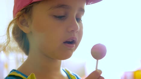 Little-girl-enjoying-a-lollipop-while-staring-at-camera.-Child-eating-candy,-sweets,-sugar