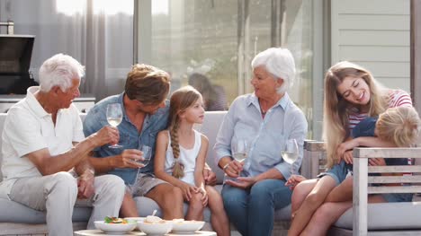 Multi-Generationen-Familie-im-freien-Getränke-und-Snacks-zu-Hause-genießen