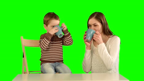 Hijo-con-su-madre-bebiendo-té-en-una-pantalla-verde