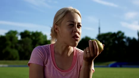 Frau-zu-essen-Apfel-im-Sonnenlicht-auf-Feld