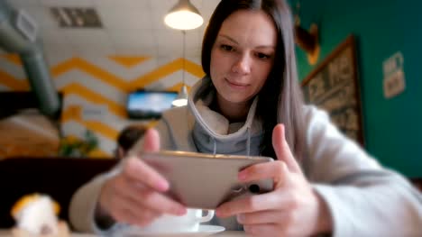 Junge-Frau-Brünette-spielt-ein-Mobiltelefon-im-Café-sitzen.