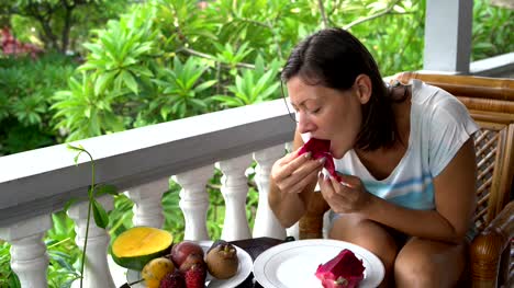 Frau-isst-Pitahaya-auf-dem-Balkon-sitzen