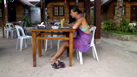 A-woman-sits-at-a-table-in-the-restaurant,-eats-and-drinks-cocktail