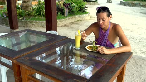 Eine-Mädchen-sitzt-in-einem-Restaurant-auf-der-Straße-und-essen-Fleisch-mit-Gemüse