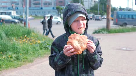 Boy-eating-a-bun-on-the-street.