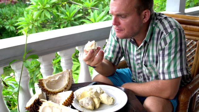 Ein-Mann-sitzt-auf-dem-Balkon-Essen-durian