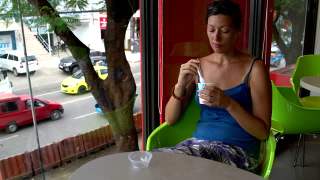 Frau-aus-einem-Einweg-Becher-sitzen-an-einem-Tisch-in-einem-Café-ein-Eis-essen