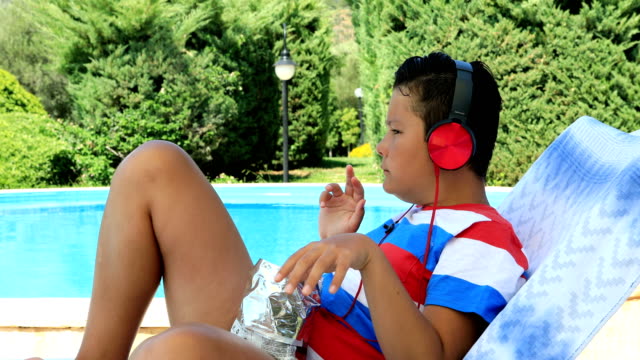Young-boy-listening-to-music-near-the-pool