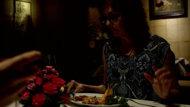 Mujer-sentada-en-una-mesa-en-un-restaurante,-comer,-hablar,-tintineo-de-vasos-y-bebe-vino-tinto