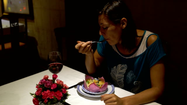 Mädchen-am-Tisch-essen-Gericht-in-Form-einer-Lotusblüte-und-trinken-Rotwein