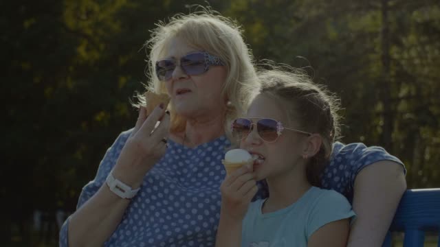 Kid-eating-eating-icecream-with-grandmother-outdoor