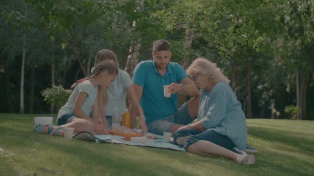 Familia-relajado-con-picnic-en-el-parque-de-verano