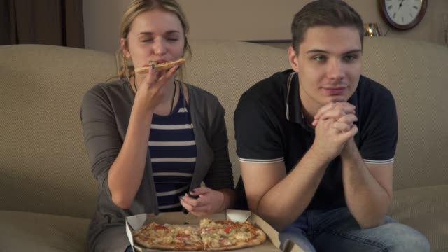 Junges-Paar-mit-einer-Schachtel-Pizza-sitzt-auf-der-couch