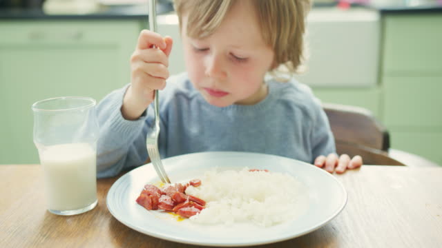 Lindo-niño-comer-Chorizo-con-un-tenedor-en-la-mesa