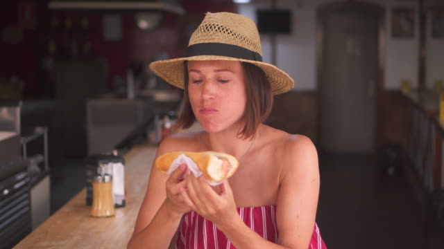 Woman-eating-hotdog-in-the-cafe