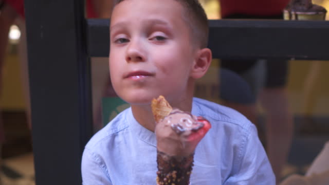 Young-boy-eating-ice-cream-on-bench-outdoors