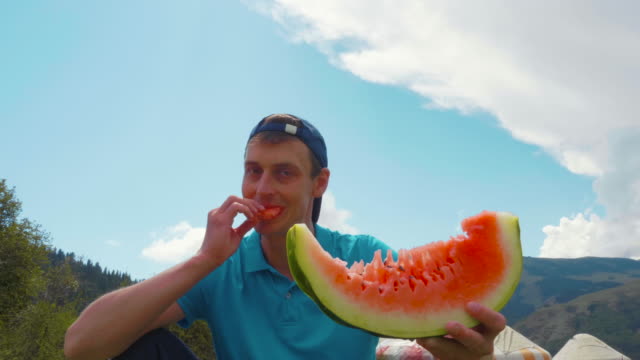 Porträt-gut-aussehender-Mann-essen-frische-Wassermelone-am-Sommertag-im-freien