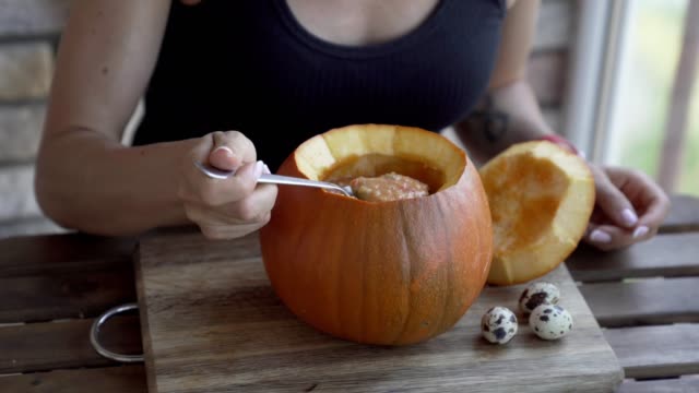 Happy-young-woman-eating-pumpkin-soup-in-kitchen