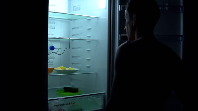 Hungriger-Mann-sucht-zu-Essen-im-Kühlschrank-in-der-Nacht.-Ungesunde-Lebensmittel-Konzept