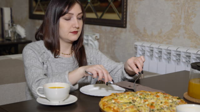 Pizzeria.-Young-woman-takes-a-slice-of-pizza-with-cutlery