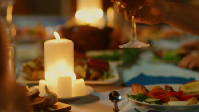 Am-Abend-Nahaufnahme-Schuss:-Mann-wirft-Glas-auf-dem-Tisch-und-schlägt-einen-Toast.-Warme-Atmosphäre-mit-Freunden-und-Familie