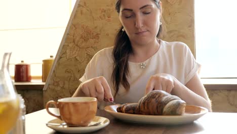 Beautiful-woman-at-the-table-eating-a-croissant