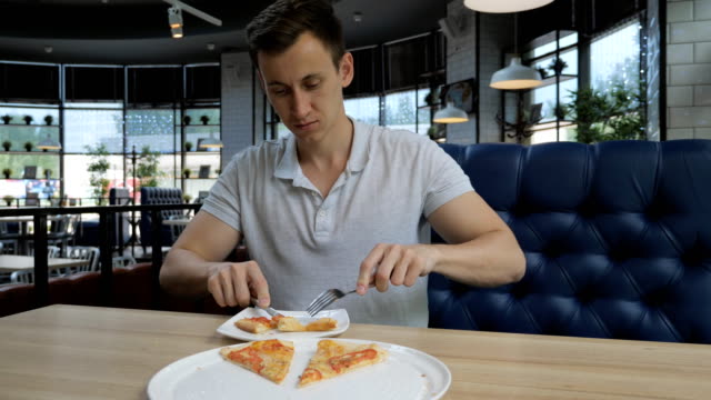 Schönen-jungen-Mann-Essen-Pizza-in-einem-café